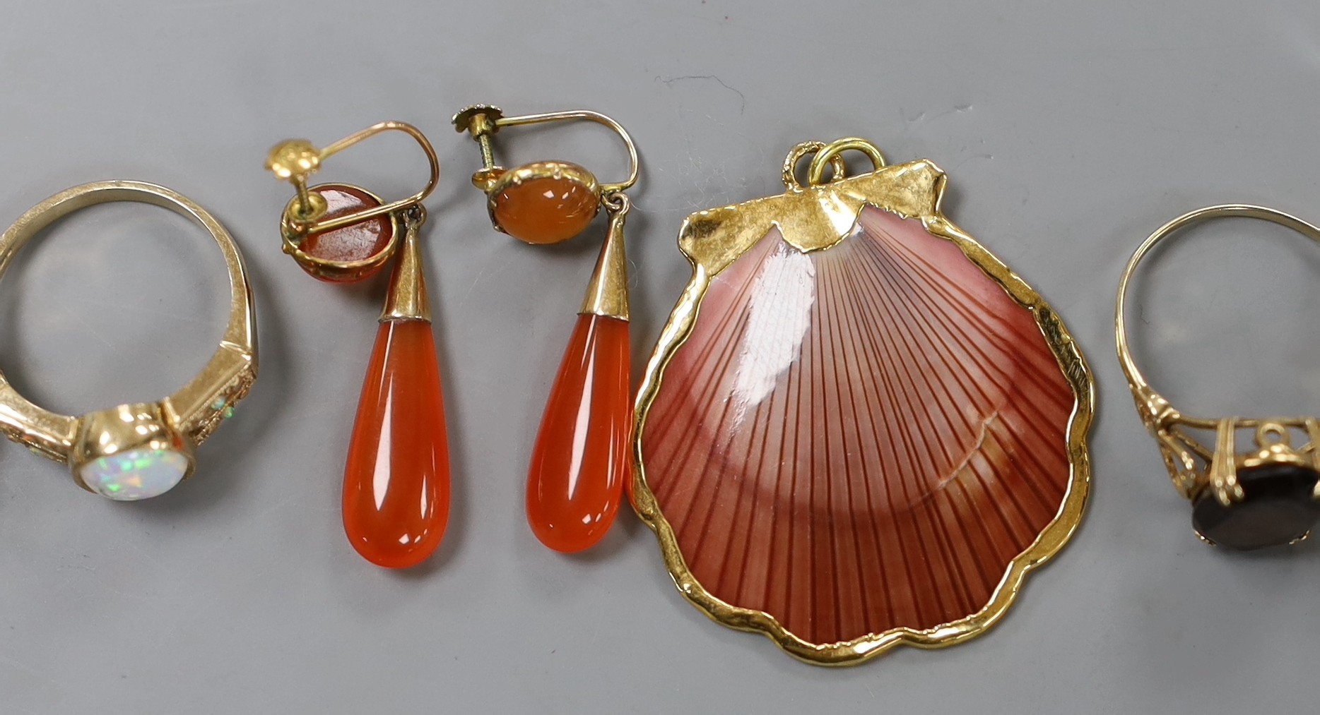 Eight assorted modern 9ct gold and gem set dress rings, a pair of 9ct and carnelian set drop earrings, gross weight 30.7 grams. and a yellow metal mounted shell pendant.